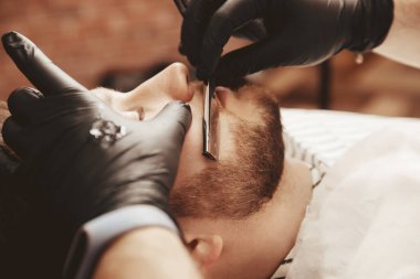 Berber dükkanında jiletle sakal kesmek. Yakın çekim.