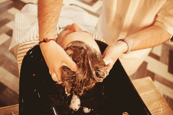 Masáž hlavy. Holič si myje vlasy šamponem v holičství — Stock fotografie