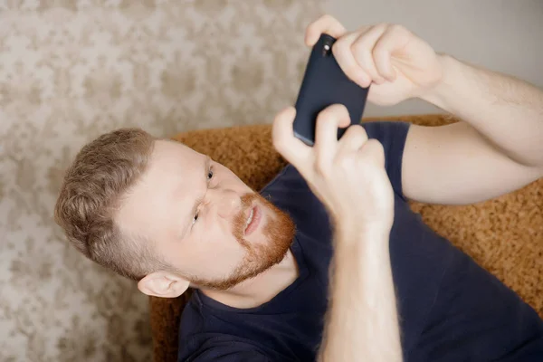 L'uomo gioca al cellulare, lo tiene in mano, faccia aggressiva — Foto Stock