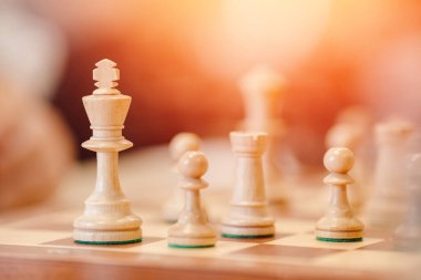 Oyun için figürleri olan satranç tahtası, parlak ışık. İnsanlar arka planda oynuyor