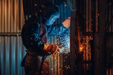 Profesyonel kaynakçı koruyucu maske metal üzerinde kaynak çalışmaları yapar. Endüstriyel işçi kavramı