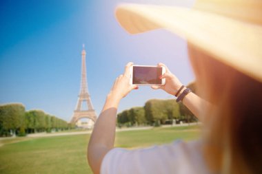 Şapkalı seyahat blogger genç kadın Paris'te telefonda Eyfel Kulesi'nin fotoğrafını çeker, Fransa