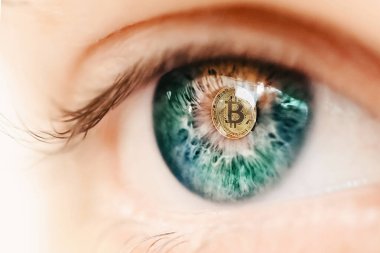 Öğrencisinde bitcoin logosu olan kişinin gözü.