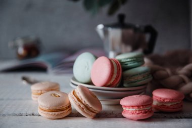 Gri nötr çatı arkaplanı üzerine Macaron, farklı renkte tabakta dur.