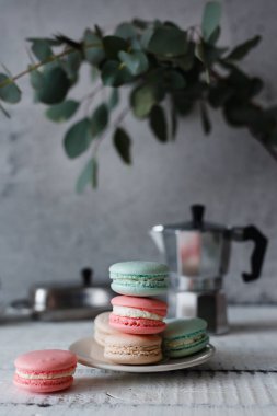 Gri nötr çatı arkaplanı üzerine Macaron, farklı renkte tabakta dur.