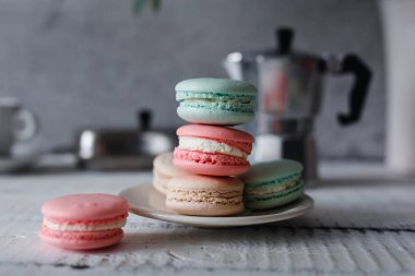 Gri nötr çatı arkaplanı üzerine Macaron, farklı renkte tabakta dur.
