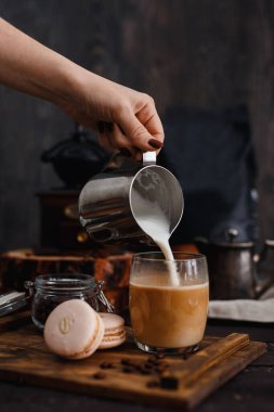 Kahvaltıda. Kızın eli kahveye süt koyuyor. Makarnanın yanında, öğütücüde.