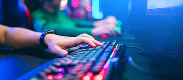 Professional cyber video gamer studio room with personal computer armchair, keyboard for stream in neon color blur background. Soft focus