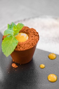 Çikolata şekerli nane filizi bir kap toprak tatlı pudingi ve tabağında dondurma.