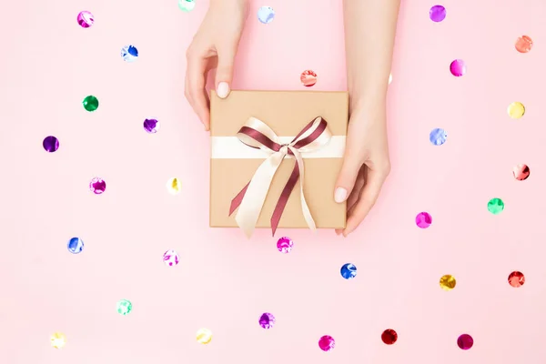 Mãos bonitas menina segurar caixa de presente presente papel artesanal no fundo rosa, vista superior. Conceito Natal, Ano Novo — Fotografia de Stock