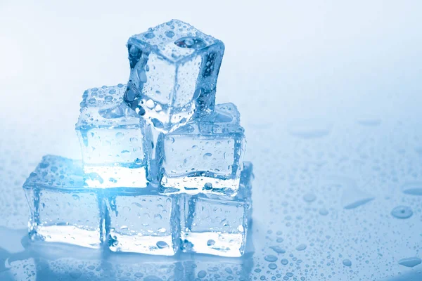 Cubos de hielo cuadrados con gotas de agua limpia sobre fondo azul — Foto de Stock