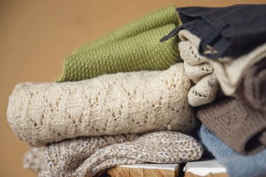 Pastel rengin yün süveterleri ahşap masada, sarı arka planda duruyor. Giysileri geri dönüşüm konsepti