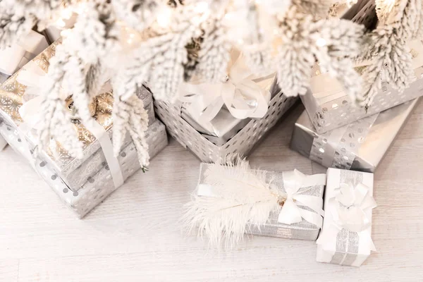 Presentes de Natal sob árvore de Ano Novo com neve artificial com iluminação dourada. Cor de prata — Fotografia de Stock