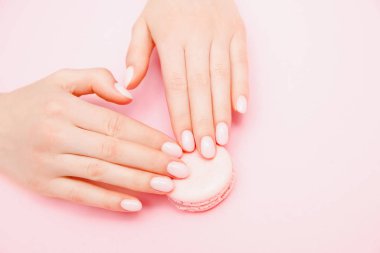 Pembe arka planda şık moda kadın manikürü. Kız el ele tutuşup kurabiye yiyor. Üst manzara, düz uzanma