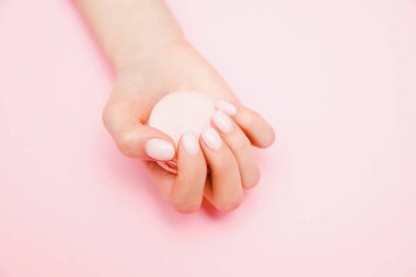 Pembe arka planda şık moda kadın manikürü. Kız el ele tutuşup kurabiye yiyor. Cilt bakımını kabul et