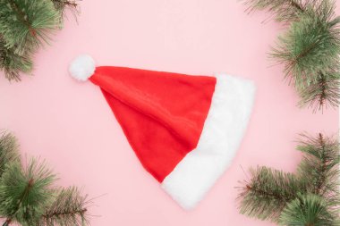 Kırmızı Noel Baba şapkası, pembe arka planda, bedavaya. Noel kıyafeti konsepti