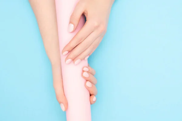 Belles mains féminines avec vernis à ongles gel manucure élégant sur fond rose et bleu, vue de dessus. Concept de soins de la peau — Photo