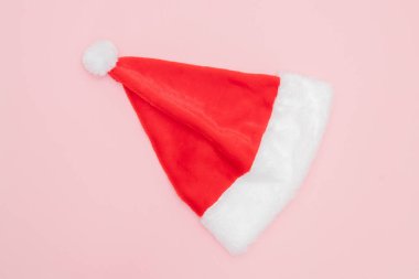 Kırmızı Noel Baba şapkası pembe arka planda. Noel kıyafeti konsepti