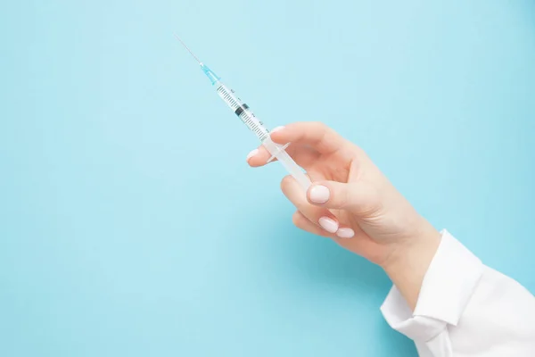 Beauty spa doctor holding syringe on blue background. Female hand with manicure — 스톡 사진