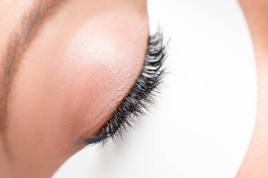 Güzellik salonunda uzun kirpikleri olan Macro fotoğrafçı kadın. Kirpik uzatma prosedürünü kabul et