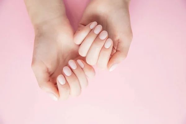 Belas mãos femininas com manicure gel polonês no fundo rosa, vista superior — Fotografia de Stock