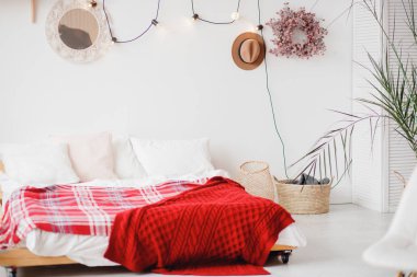 Minimalizm İskandinav tarzı yatak odası. Beyaz duvarları ve duvarlarında palmiyeli çelenkler var.