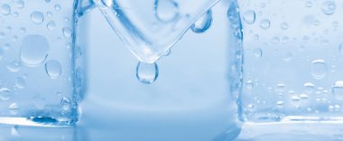 Mavi zemin üzerinde su damlaları olan buz küpleri makro kare