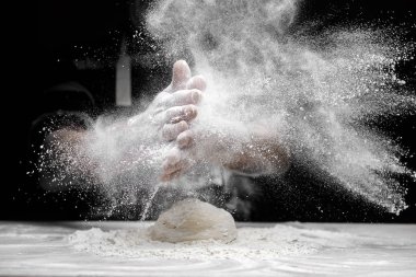 Şef el çırptı ve siyah arka planda beyaz un tozu