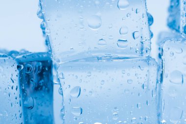 Mavi zemin üzerinde su damlaları olan buz küpleri makro kare