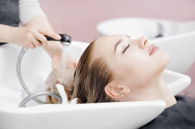 Güzeller güzeli sarışın kadın kuaförde saç yıkıyor. Kafa bakımını kabul et