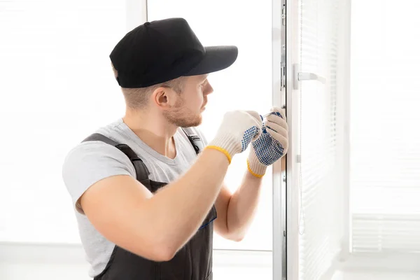 Trabalhador da construção homem usa chave de fenda para parafuso alça instalar plástico branco upvc janelas em casa — Fotografia de Stock