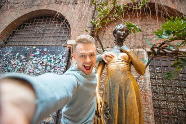 Фото мужчины, держащего в руках статую Джульетты в Вероне, Италия, улыбающегося и смеющегося. Концепция путешествия — стоковое фото