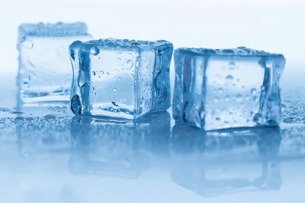 Cubos de gelo quadrado com gotas de água limpa no fundo azul — Fotografia de Stock