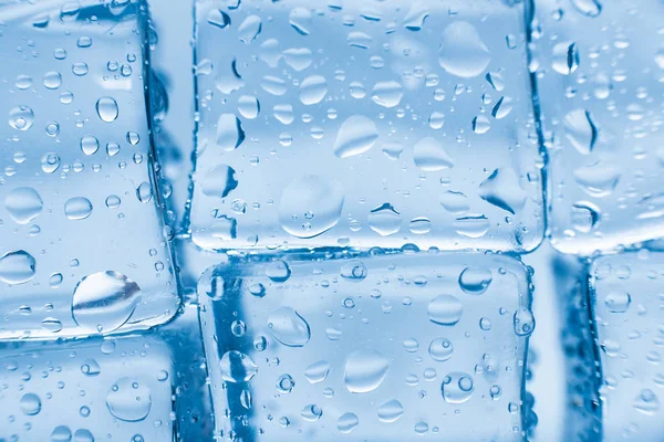 파란색 배경에 깨끗 한 물방울을 떨어뜨려 놓은 네모난 얼음 — 스톡 사진