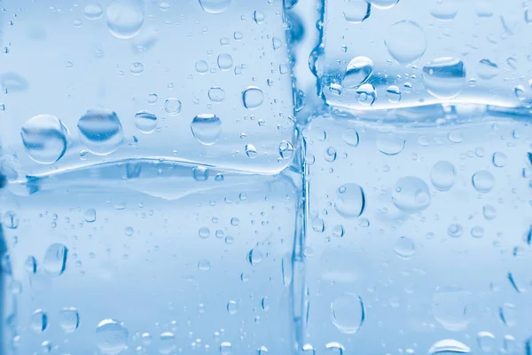 Cubos de gelo quadrado com gotas de água limpa no fundo azul — Fotografia de Stock