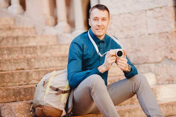 Portrait heureux photographe voyageur masculin tenant la caméra dans les mains assis sur les marches en italie, fond flou — Photo