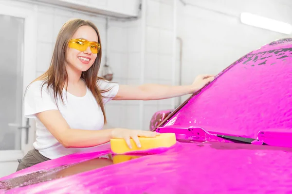 Arbeiterin mit gelbem Schwamm Autowaschanlage aus rosa Schaum — Stockfoto