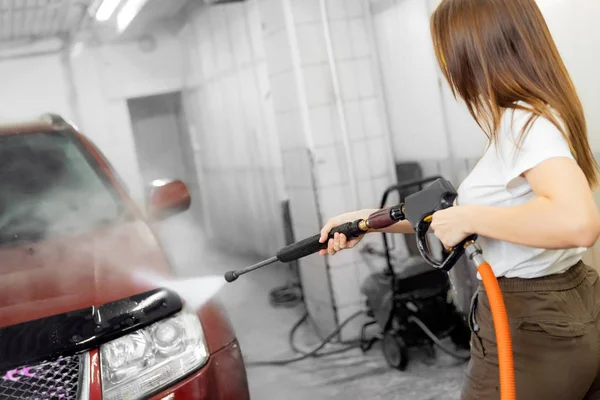 Servicio de lavado de autos. Mujer trabajadora limpiando auto usando agua de alta presión —  Fotos de Stock