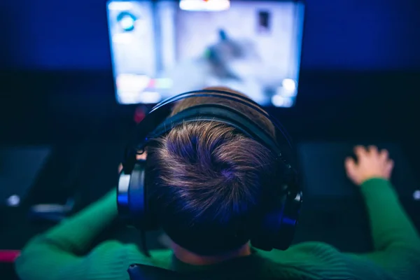 Jugador profesional jugando torneos de juegos en línea ordenador PC con auriculares, fondo rojo y azul borrosa —  Fotos de Stock