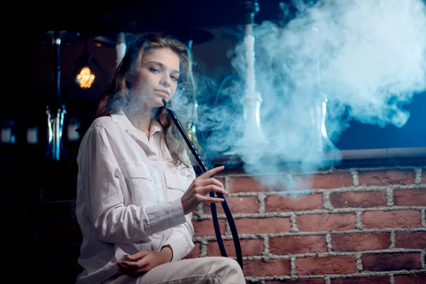 Joven hermosa mujer en club nocturno humo hookah o shisha bar, fondo azul — Foto de Stock