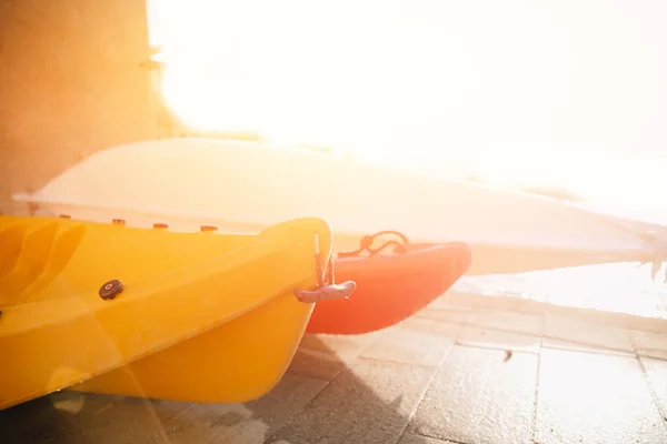 Barche in kayak di plastica gialla si trovano nel parcheggio, luce del tramonto. Viaggio concettuale sul lago fluviale — Foto Stock