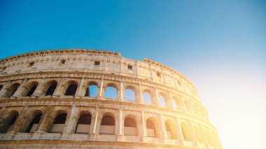 Kolezyum veya Kolezyum antik harabeler arka plan mavi gökyüzü Roma, İtalya, aşağıdan manzara, taş kemerler ve güneş ışığı