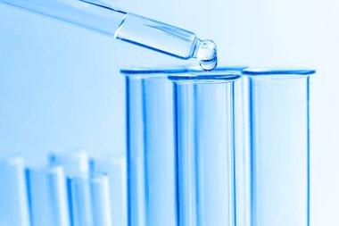 Mavi arkaplan bilimi üzerinde kimyasal pipet düşürücü ve test tüpü