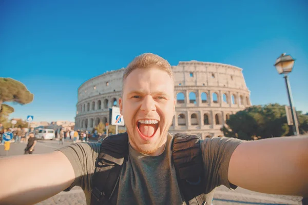 Glad kaukasisk man turist med ryggsäck tar selfie foto Colosseum i Rom, Italien. Resor resa koncept — Stockfoto