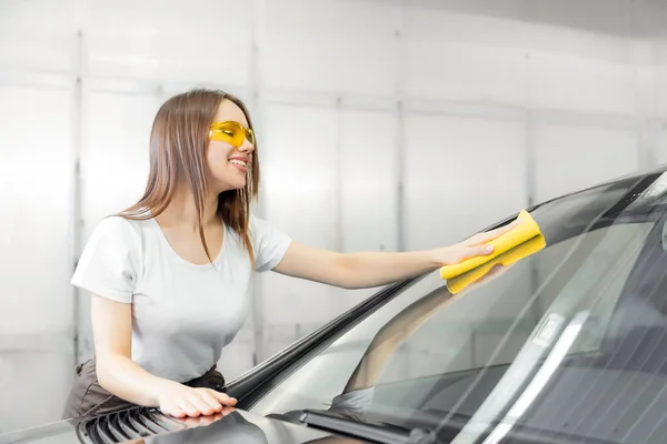 Krásné ženy pracovnice mytí čelního skla s houbou na autě, okno čistý sprej — Stock fotografie