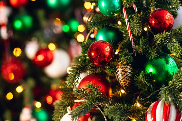 Rama de árbol de fondo de Navidad con decoraciones caramelo piruleta bastón rojo y verde bolas, con luz bokeh — Foto de Stock