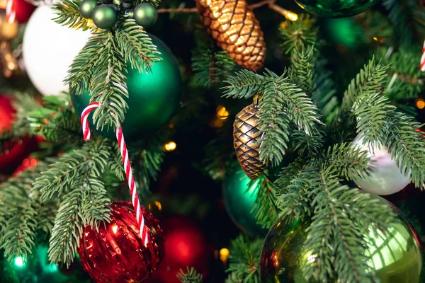Weihnachten Hintergrund Baum Zweig mit Dekorationen Zuckerstange rot und Kegel grüne Kugeln, mit Bokeh-Licht — Stockfoto