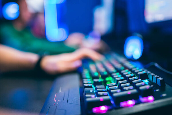 Blurred background professional gamer playing tournaments online games computer with headphones, red and blue