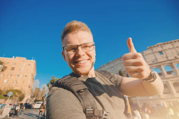 Счастливый человек турист с рюкзаком в очках делает селфи фото Колизей в Риме, Италия — стоковое фото