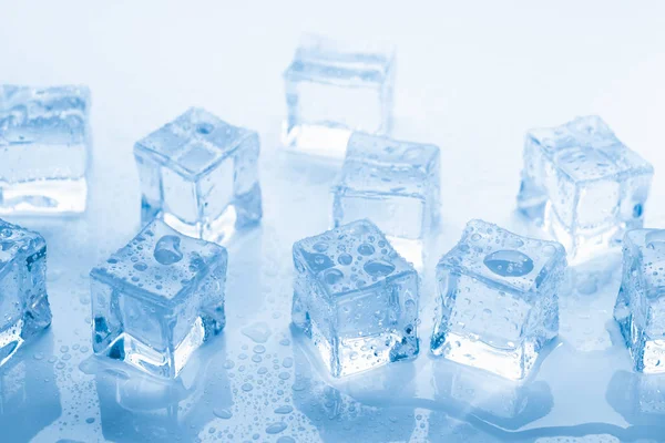 Cubos de hielo cuadrados con gotas de agua limpia sobre fondo azul —  Fotos de Stock